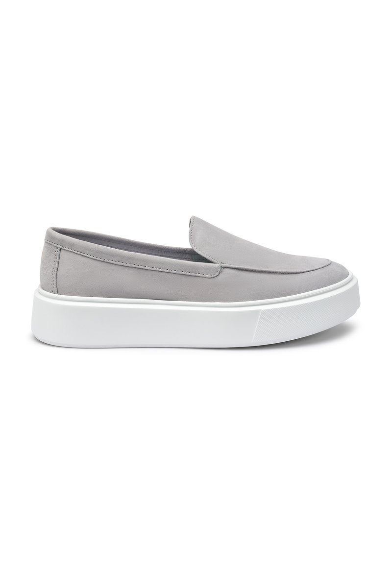 Scarpe slip-on grigie con una finitura in suede liscia, punta arrotondata e suola piatta bianca spessa. Design minimalista senza hardware visibile.