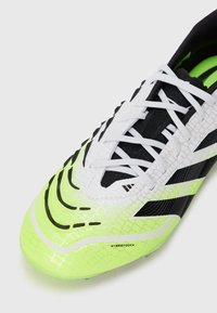 Bright yellow-green soccer shoe with a textured synthetic upper, black accents, white laces, and a distinct pattern along the toe.