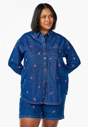 Camicia di denim con una vestibilità relax e ricami colorati di fragole, abbinata a pantaloni corti coordinati. Presenta una chiusura frontale con bottoni e una tasca.