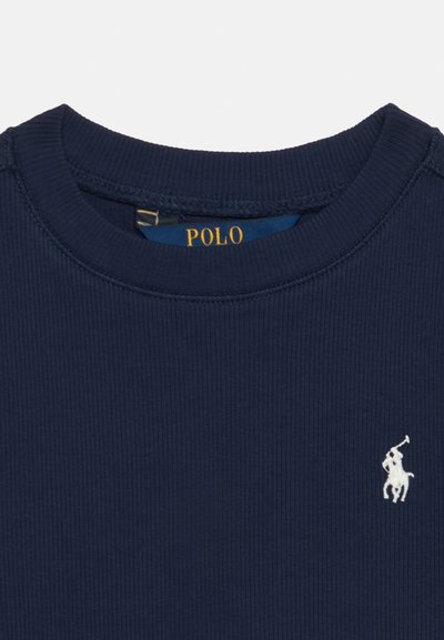 Μπλε ναυτικού ribbed T-shirt με στρογγυλή λαιμόκοψη, λευκό κεντημένο λογότυπο Polo Ralph Lauren στο στήθος και κίτρινη ετικέτα "POLO" στο εσωτερικό του γιακά.