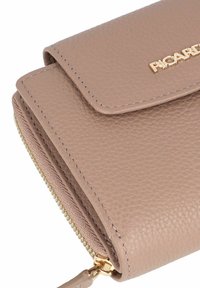 Portefeuille en cuir beige avec une finition texturée, doté d'un compartiment zippé et de quincaillerie en doré. Se ferme avec un rabat.