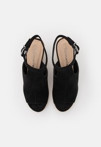 Černé semišové sandály na podpatku s otevřenou špičkou, nastavitelným páskem se stříbrným kováním a přírodní texturovanou podešví. Velikost 38.