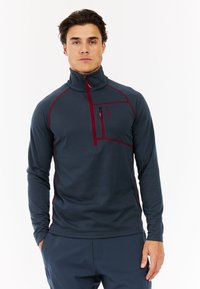 Herren Pullover mit Viertelreißverschluss in Dunkelblau mit roten Akzenten, aus strukturiertem Stoff, mit einer gefütterten Brusttasche und hohem Kragen.