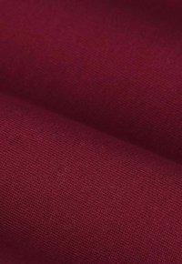 Burgunderfarbener Stoff mit einer glatten Textur, der ein feines, gleichmäßiges Gewebe aufweist. Die Farbe ist tief und reichhaltig, was ihr Aussehen und ihre Haltbarkeit verbessert.