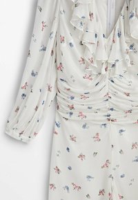 Robe à motifs floraux en tissu blanc léger. Présente un col froncé, des manches longues et des détails froncés à la taille.