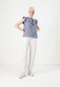 Bluză bleu cu dungi, mâneci volănaș și un nod în față, asociată cu pantaloni largi albi și adidași albi. Design simplu și casual.