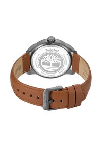 Hnedý kožený náramkový hodinky so strieborným nerezovým puzdrom, kontrastným prešívaním a logom Timberland na sponke. Vodotesný dizajn.
