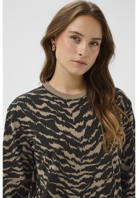 Tmavě zelená mikina s béžovým abstraktním vzorem. Má žebrovaný výstřih a volný střih, s měkkou texturou látky.