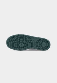 Semelle de chaussure en caoutchouc vert foncé avec motifs de bande de roulement circulaires et petit logo Nike embossé au centre.