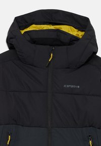 Black padded jacket with a hood, featuring a yellow lining, zipper closure, and contrasting dark gray lower section. Brand logo displayed.