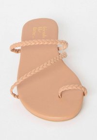 Beige värvi lame sandaalid, millel on punutud rihmad. Sile pind, ümmargune varvas, minimalistlik disain. Siseosale on kuldsete tähtedega trükitud tekst "sõbrad nagu need...".