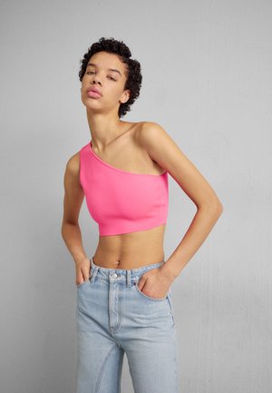Top corto de un solo hombro en tela de color rosa brillante, combinado con jeans de cintura alta en azul claro. Textura suave sin patrones o adornos visibles.