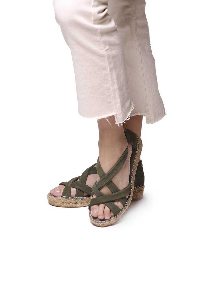 Žalios suede wedges sandalai su kryžminiais diržais, jute dengtu padu ir atvirais pirštais. Stilizuoti su šviesius spalvos trumpais kelnais.