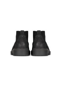 Botines de ante negro con una superficie texturizada, paneles laterales elásticos y suelas de goma, que ofrecen un diseño minimalista y un tacón apilado.