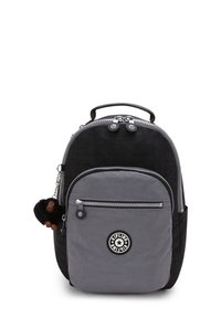 Schwarzer und grauer Nylon-Rucksack in runder Form, mit Reißverschluss-Taschen und einem pelzigen Affen-Schlüsselanhänger. Mit einem Logo-Patch auf der Fronttasche.