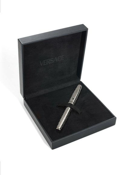 Versace rašiklis, laikomas juodame dėkle su minkšta pamušalu. Rašiklis pasižymi blizgiu sidabriniu apdailos paviršiumi ir tekstūruotu deimanto raštu per visą kūną.