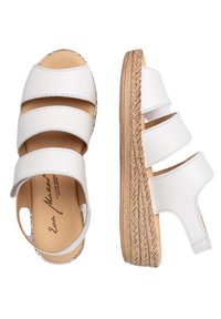 Las sandalias de cuña de cuero blanco cuentan con tres tiras anchas, un respaldo abierto y una suela trenzada similar a una cuerda con una plantilla lisa y natural.