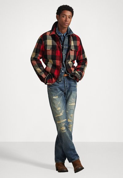 Plaid fleece jacket with red, black, and beige squares, layered over a denim shirt. Worn with distressed blue jeans and brown boots.