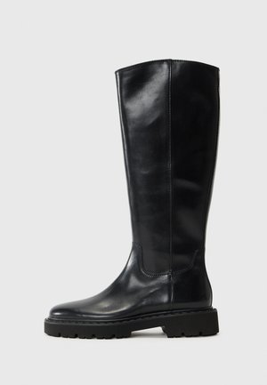 Zwarte leren kniehogere laars met een gladde afwerking, ronde teen, stevige rubberen loopzool en minimale stikseldetails.
