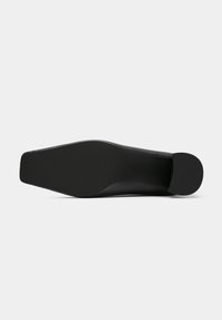 Suola nera di scarpa con una superficie liscia e strutturata e una punta arrotondata. Presenta un design elegante e stretto adatto per abbigliamento formale.