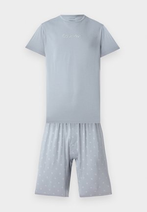 Light blue short-sleeve Calvin Klein shirt with logo on chest paired with matching shorts featuring small repeating logo pattern.
