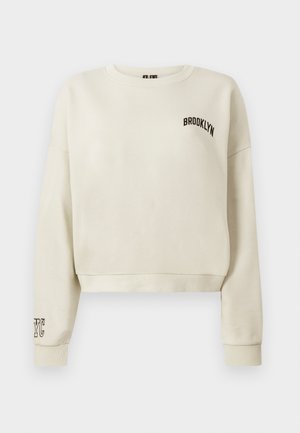 Kreemivärvi lühikeste varrukatega sweatshirt ribidega mansetid. Ees on musta värvi tikandiga "BROOKLYN" ja vasakul varrukal "NYC".