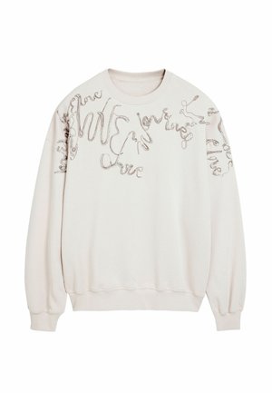 Sweatshirt beige clair avec un script texturé et brodé dans différents styles sur le devant, doté de poignets et d'un ourlet côtelés.