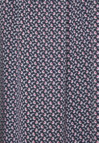 Tessuto blu navy con un denso motivo di piccoli fiori bianchi, ognuno con un centro rosso, disposti in modo ravvicinato in un design ripetitivo.