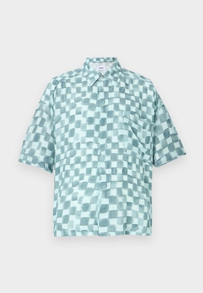 Kratka srajca s kratkimi rokavi v svetlo modri barvi s karirastim vzorcem različnih odtenkov. Ima ovratnik in žep na prsih.