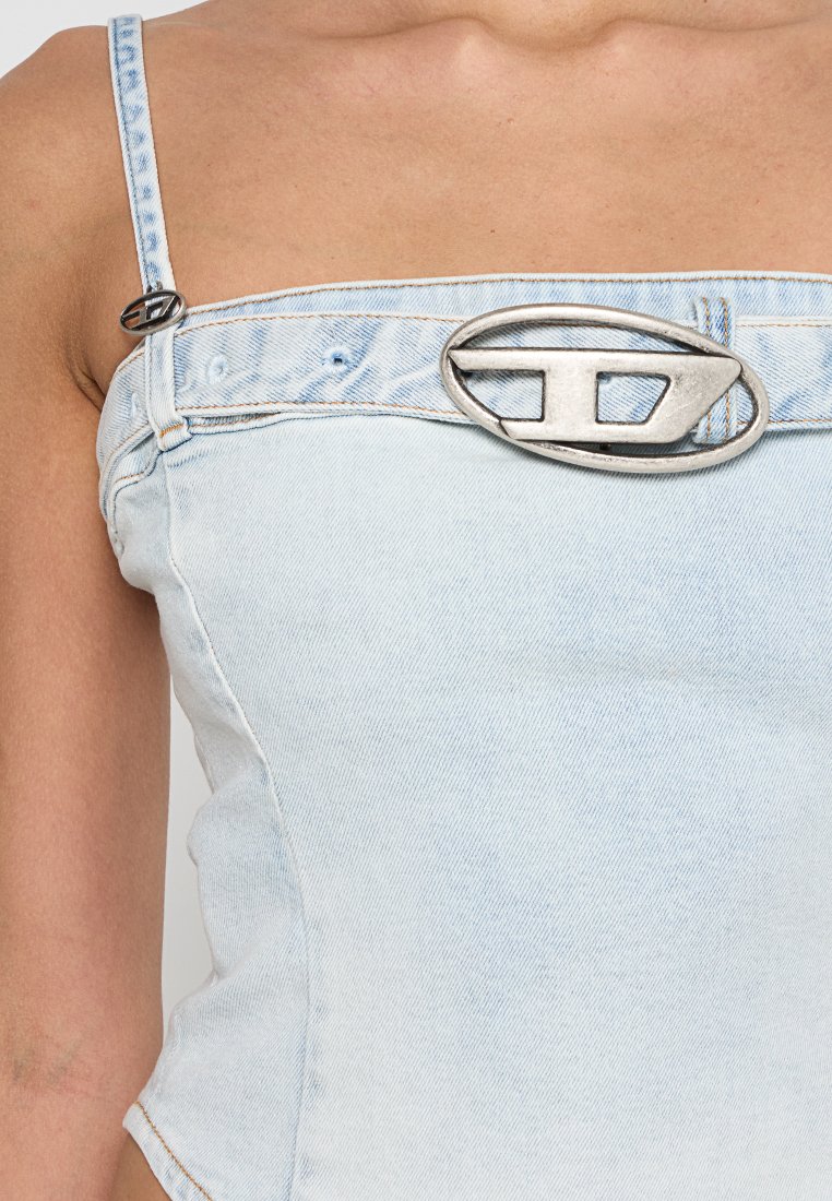 Hellblaues Jeans-Bodysuit mit verstellbaren Trägern und einer großen silbernen ovalen Schnalle in der Mitte. Glatte Textur mit einer taillierten Passform.