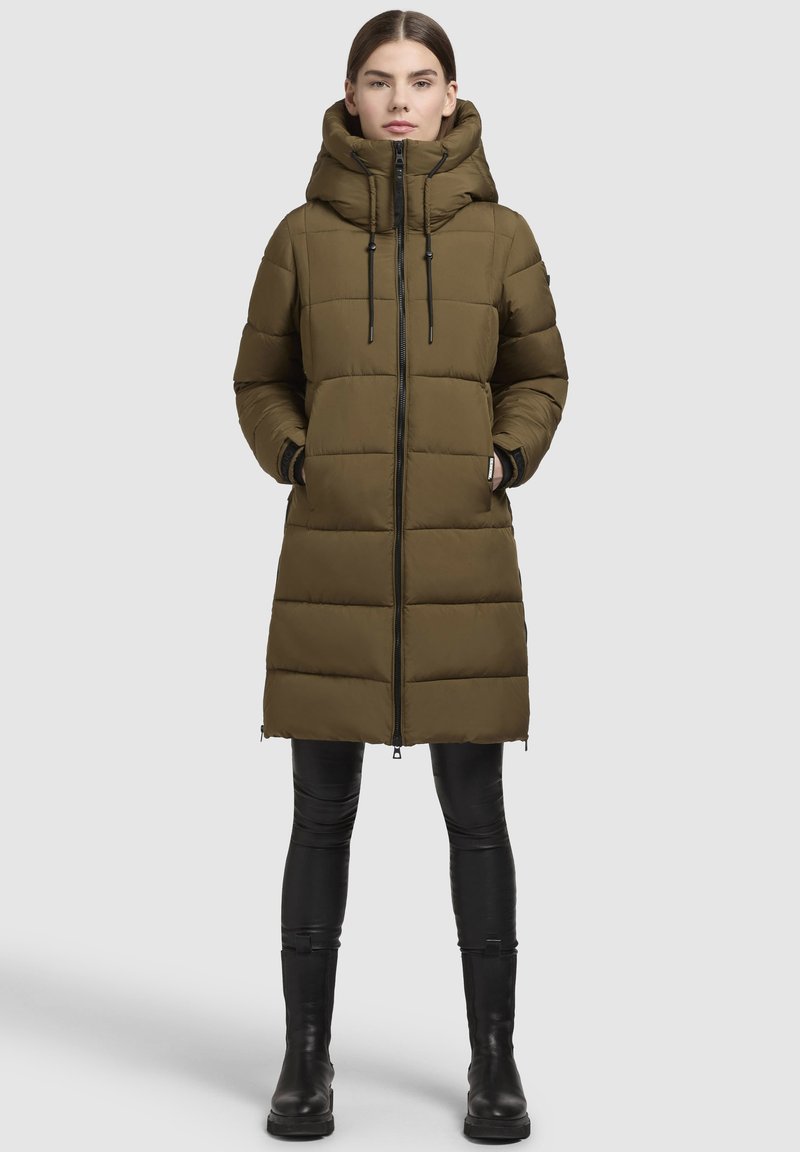 Abrigo acolchado de color verde oliva con cuello alto, cremallera frontal y dos bolsillos laterales. Presenta un diseño elegante y largo con puños elásticos.