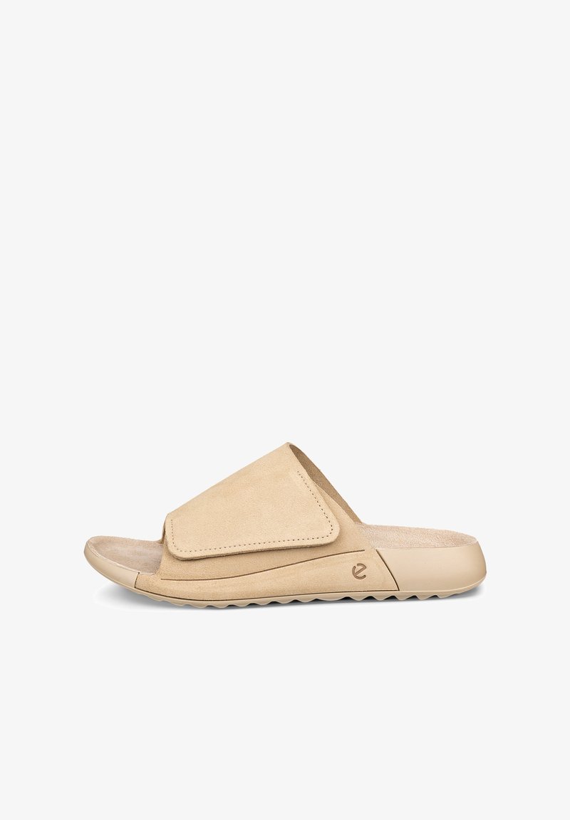 Sandale ouverte beige à enfiler avec une large bride ajustable et une semelle texturée, conçue pour un usage décontracté en intérieur comme en extérieur.