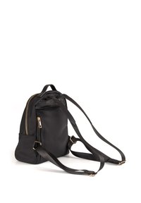 Zaino nero realizzato in tessuto liscio, con chiusura a zip, spallacci regolabili e dettagli in metallo color oro. Design compatto con forma arrotondata.