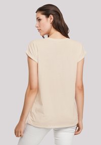 Beige short-sleeve t-shirt with a relaxed fit and rounded neckline. Soft fabric with a smooth texture, featuring roll-up sleeves and a curved hem.