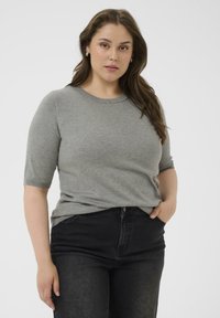 Suéter gris de manga corta con textura de punto y cuello redondo, que presenta un detalle en forma de cuentas plateadas, combinado con jeans oscuros.