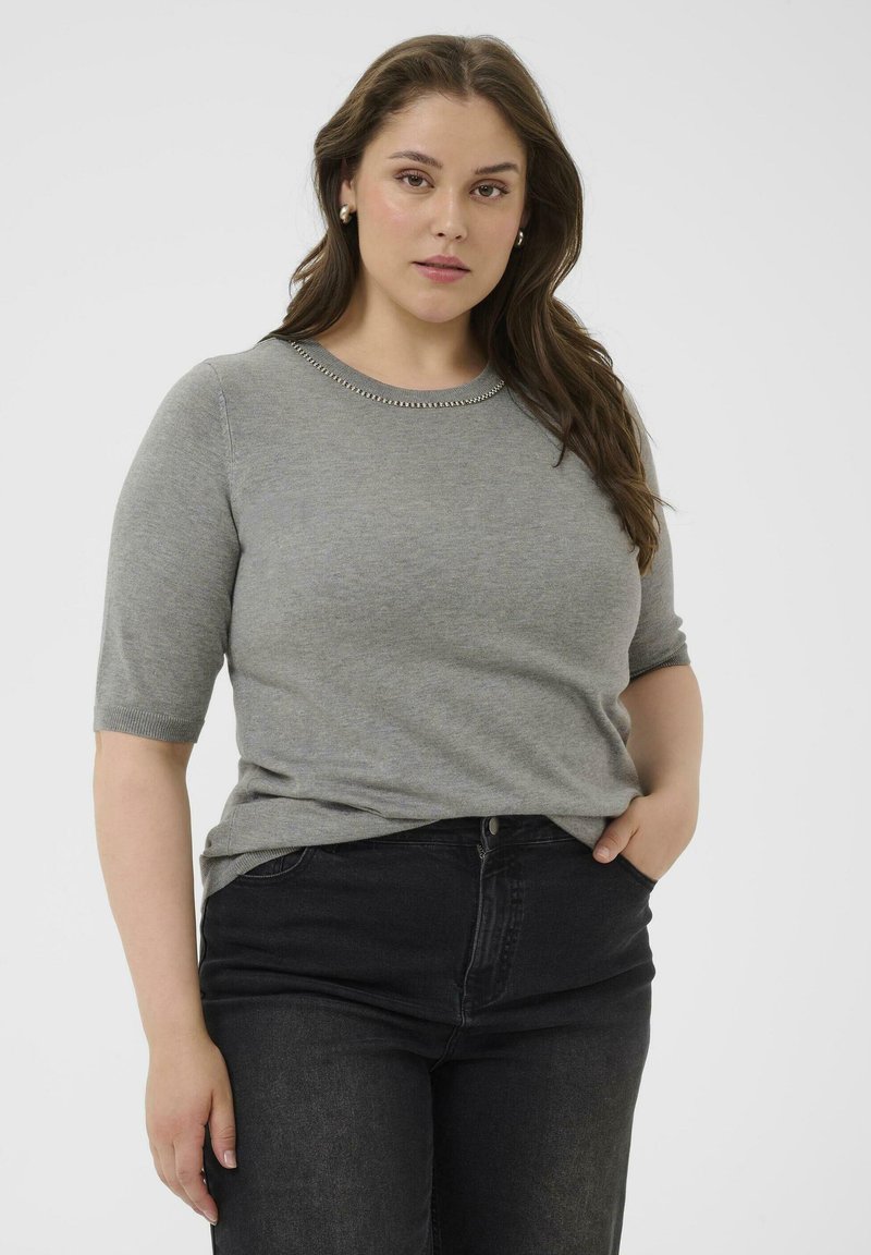 Suéter gris de manga corta con textura de punto y cuello redondo, que presenta un detalle en forma de cuentas plateadas, combinado con jeans oscuros.