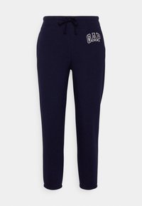 Mörkblå sweatpants med dragsko i midjan, ribbade muddar vid anklarna och broderad "GAP"-logga på vänster höft. Mjuk bomullsmaterial.