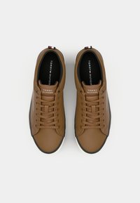 Paire de baskets en cuir marron Tommy Hilfiger avec des lacets assortis et des semelles intérieures noires, vues de dessus sur un fond blanc.