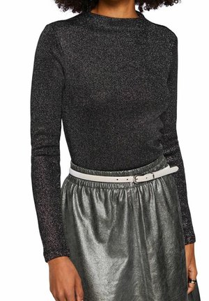 Haut noir à manches longues avec un effet scintillant, doté d'un col montant et assorti à une jupe argentée métallique et une ceinture blanche.