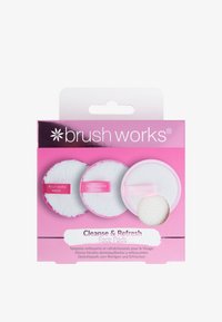 Tres almohadillas faciales redondas con texturas variadas: dos almohadillas blancas y suaves con detalles rosas etiquetadas como "Eliminar" y "Limpiar", y una almohadilla blanca texturizada etiquetada como "Exfoliar". El embalaje es de color rosa.