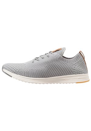Baskets de sport gris clair avec une tige en maille, un motif texturé, un système de laçage et une semelle intermédiaire blanche. Semelle extérieure en caoutchouc avec un accent de talon beige.