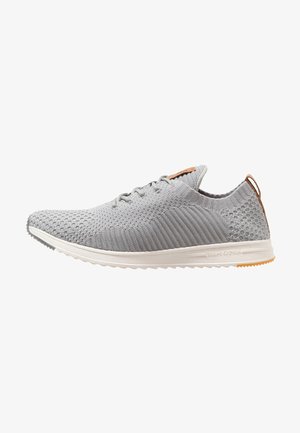 Scarpe da ginnastica grigio chiaro con tomaia in maglia, pattern testurizzato, chiusura con lacci e suola intermedia bianca. Suola in gomma con un accento di tacco beige.