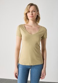 Korte ermer, v-hals t-skjorte i lys beige, laget av mykt stoff med slim fit. Har en jevn tekstur og minimale sømmer.