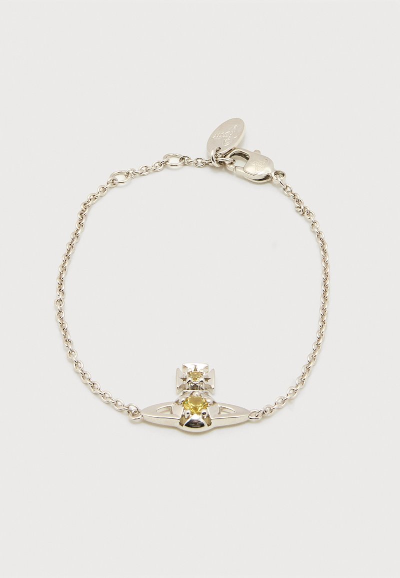 Ασημένιο βραχιόλι αλυσίδας με κεντρική οβάλ κίτρινη πέτρα και μικρή λεπτομέρεια σε σχήμα σταυρού, με κούμπωμα αστακού και μικρή ετικέτα της μάρκας.