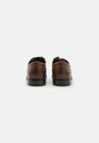Chaussures en cuir marron avec une finition lisse, bout arrondi et semelle en caoutchouc noir. Couture détaillée sur les côtés et à l'arrière. Design à deux œillets.