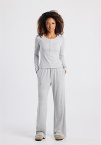 Graues Loungewear-Set bestehend aus einem langärmeligen Hemd mit Knopfleiste und Rundhalsausschnitt sowie einer lässigen Hose mit elastischem Bund. Weiche Textur.