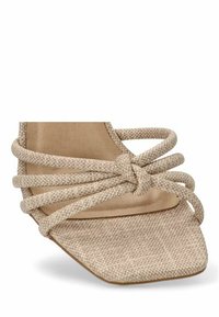 Sandal de tela tejido beige con punta cuadrada, múltiples correas anudadas y plantilla suave. El diseño enfatiza la textura y un estilo minimalista.