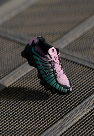 Baskets Nike avec un dessus en mesh rose et vert, accents noirs, design épuré et semelle ondulée distincte pour un meilleur amorti.