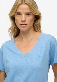 Lyseblå v-neck t-shirt lavet af blødt, åndbart stof. Har et diskret logo på brystet og en afslappet pasform med korte ærmer.