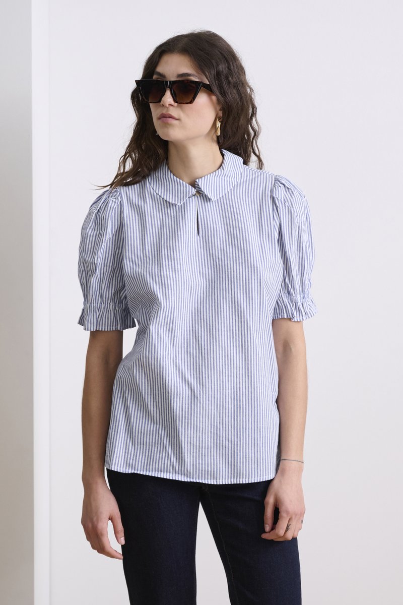 Camicia a maniche corte blu e bianca a righe con colletto, caratterizzata da maniche a sbuffo e un piccolo dettaglio con bottone al collo.